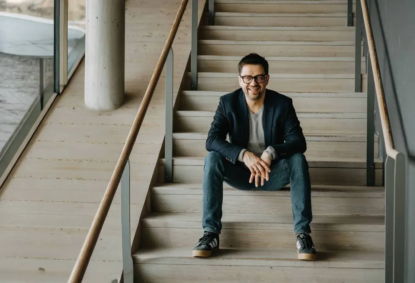 Andreas Grott – Coach für Mindful Leadership im Change – sitzt entspannt auf einer Holztreppe